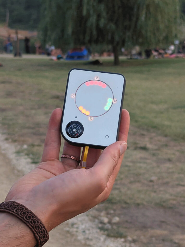 Person holding a Buddycompass festival tracker at a music festival.