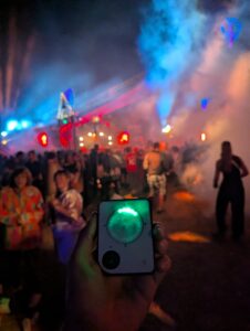 Person holding Buddycompass festival tracker at night.