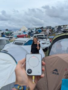 Person holding a Buddycompass festival tracker at a music festival.