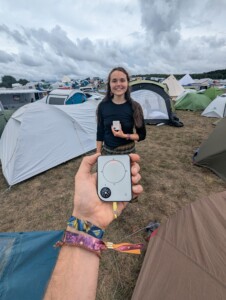 Person holding a Buddycompass festival tracker at a music festival.