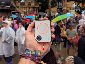 Person holding a Buddycompass festival tracker at a music festival.