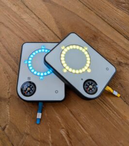 Two Buddycompass festival trackers with colorful LED lights