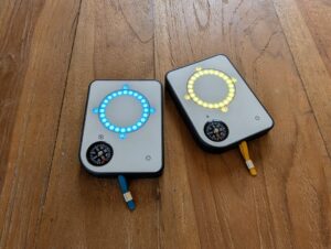 Two Buddycompass festival trackers with circular lights