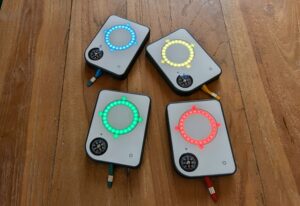 Four Buddycompass festival trackers with colorful LED rings